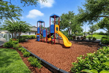 A playground with a yellow slide and a blue and red structure.